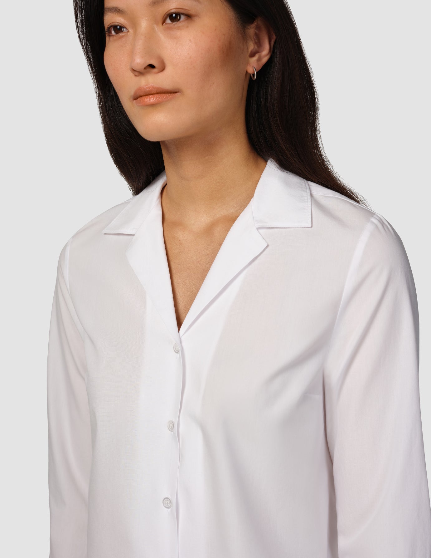 A woman wearing a white Madison Shirt with a notched collar and long sleeves.